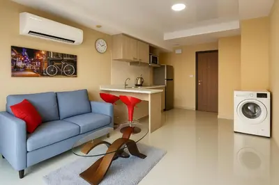 a living room with a blue couch and a washing machine at 1 bedroom Naiharn Beach Condo in Rawai Beach