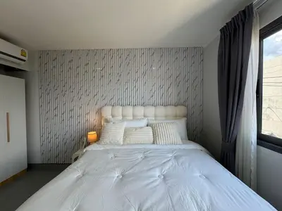 a bedroom with a large white bed with a window at Condo for rent chalong rawai 305 in Ban Klang