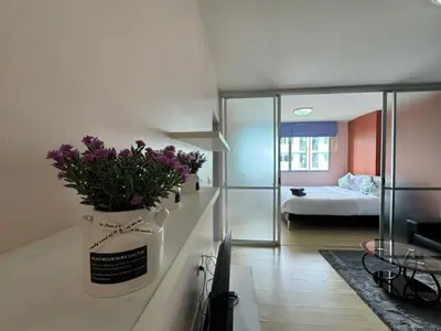 a living room with a vase with purple flowers in it at Dcondo kathu phuket in Kathu