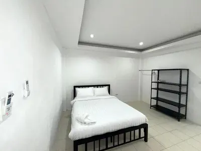 a bedroom with a bed with white sheets and a shelf at Patong Canal Villa 110 in Patong Beach