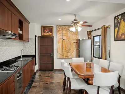 a kitchen with a wooden table and white chairs at 3 Bedrooms - 2 floor with garden in Prime Location in Thalang