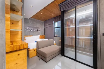 a small bedroom with a bed and a chair at Relife Apartments by Tropiclook - Fast WiFi , Pool and Gym in Phuket Town
