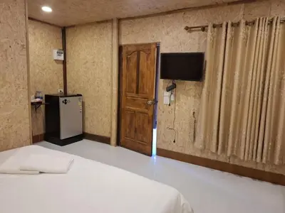 a room with a bed and a refrigerator and a door at ฟาดิลบังกะโล Fadel bungalow in Ko Nui