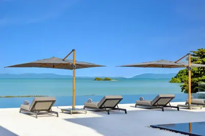 a group of chairs and umbrellas on a beach at Villa Amarasara in Phuket Town