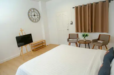 a bedroom with a bed and a tv and chairs at RQ Phuket Patong Beach by Collection O in Patong Beach