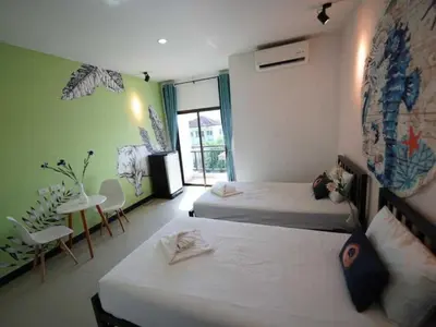 a bedroom with two beds and a table and chairs at RQ Phuket Patong Beach by Collection O in Patong Beach