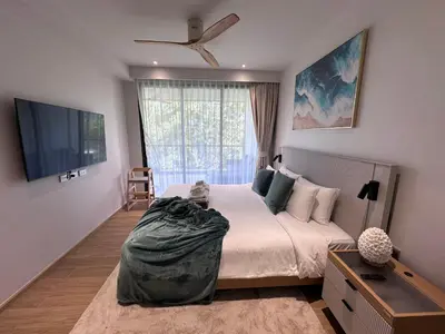 a bedroom with a large bed and a flat screen tv at 2 bdr Apartments Laguna Beachside 50m from Bangtao Beach in Bang Tao Beach