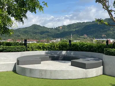 a circular bench in a park with mountains in the background at 1 bdr Mountain View Apartment 50 m from Bangtao Beach in Bang Tao Beach
