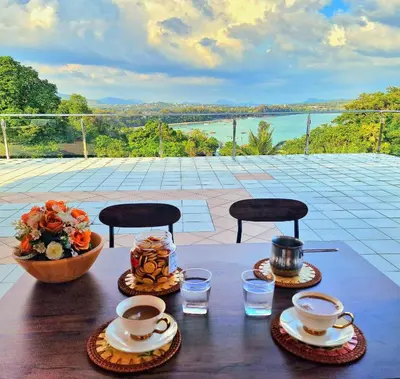 a table with two cups and a bowl of flowers at Phuket Arkadia Home in Nai Harn Beach