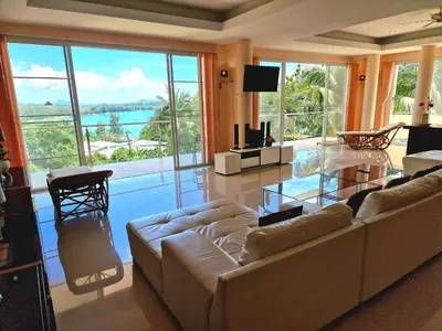 a living room with a couch and a glass table at Phuket Arkadia Home in Nai Harn Beach