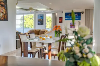 a dining room and living room with a table and chairs at Phuket Arkadia Home in Nai Harn Beach