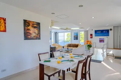 a dining room and living room with a table and chairs at Phuket Arkadia Home in Nai Harn Beach