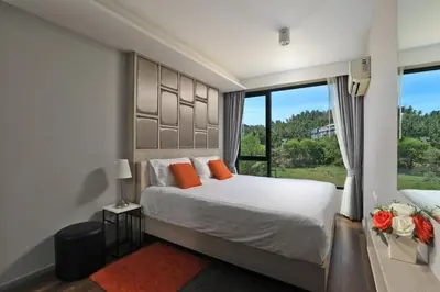 a bedroom with a bed with orange pillows and a window at 6th avenue surin in Surin Beach