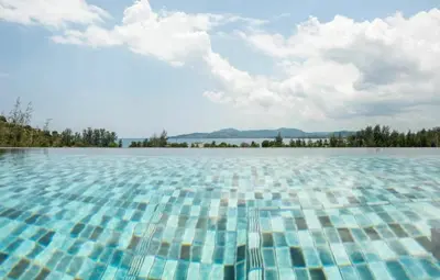 a large pool of water with trees in the background at 6th avenue surin in Surin Beach