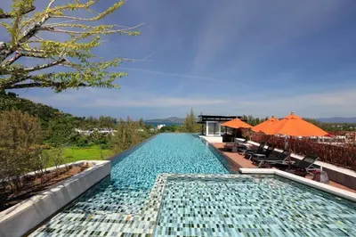 a swimming pool with orange umbrellas next to a resort at 6th avenue surin in Surin Beach