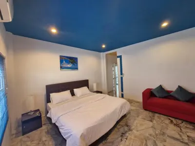 a bedroom with a bed and a red couch at Superb 3 Bed Pool Villa in Ban Saiyuan (1)