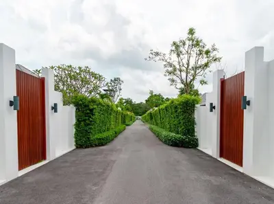a driveway with two gates and a road at Bangtao Beach Walk Villa by Taan Residence in Bang Tao Beach