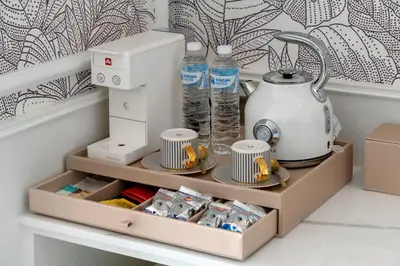 a shelf with a coffee maker and cups and water bottles at The Cyan at Patong Hotel in Patong Beach