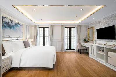 a white bedroom with a large bed and a desk at The Cyan at Patong Hotel in Patong Beach