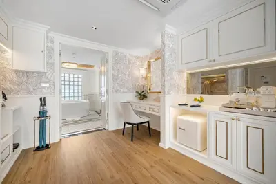 a kitchen with white cabinets and a table and a chair at The Cyan at Patong Hotel in Patong Beach