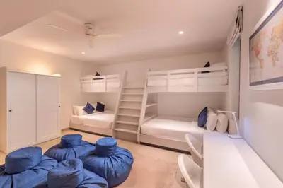 a bedroom with two bunk beds and blue chairs at Villa Narissa in Kamala Beach