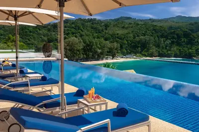 a pool at a resort with blue chairs and an umbrella at Villa Narissa in Kamala Beach