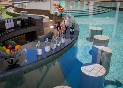 a swimming pool with a bar with bottles of wine at Utopia Phuket Naiharn Beach Grand Resort & Spa in Rawai Beach