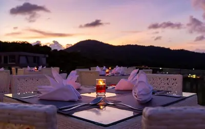a table with a glass of wine on top at Utopia Phuket Naiharn Beach Grand Resort & Spa in Rawai Beach