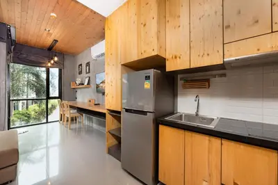 a kitchen with a stainless steel refrigerator and wooden cabinets at Relife Sol 2 min to Nai Harn beach by TropicLook in Rawai Beach