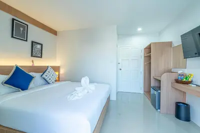 a bedroom with a large white bed and a kitchen at Seaside Patong House - Newly Open in Patong Beach