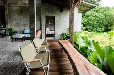 a porch with two chairs and a bed at Nana Villa in Ko Yao Noi