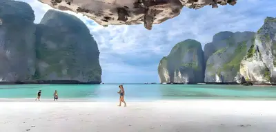 a woman walking on a beach with limestone formations at xx BAO Patong Beach Phuket - เบา ป่าตองบีช in Patong Beach