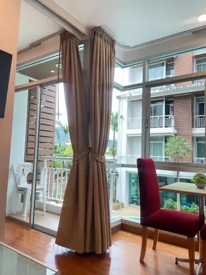 a living room with a large window and a red chair at Sabai Stay in Patong Beach