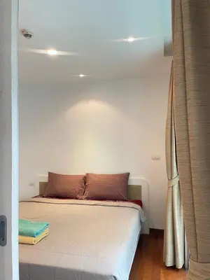 a bed in a room with a white wall at Sabai Stay in Patong Beach