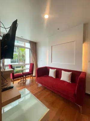 a living room with a red couch and a tv at Sabai Stay in Patong Beach