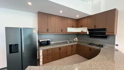 a kitchen with wooden cabinets and a stainless steel refrigerator at Ocean home in Laguna Phuket