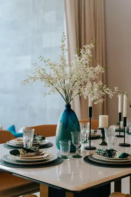 a dining room table with a blue vase with flowers at Botanica Foresta Villa in Thalang