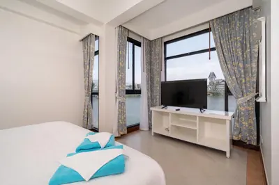 a bedroom with a bed and a tv and windows at The Lake Front Laguna Alla13 in Laguna Phuket