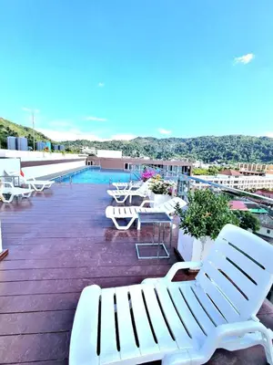 a balcony with white benches and tables and a pool at Ozone Condotel Kata Beach by Pitjira in Phuket Town