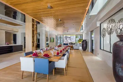 a long dining room with a long table and white chairs at Villa Amaravida in Ko Lek