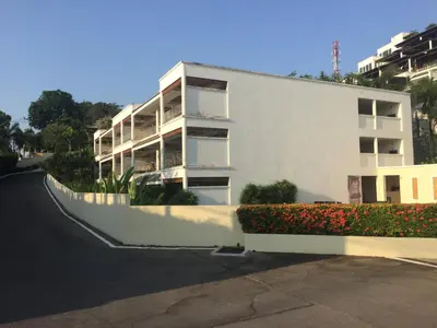 a white apartment building with flowers in front of it at Bel Air Panwa Big Apartment in south Phuket near Ao Yon Beach, 3rd floor in Ban Ao Makham