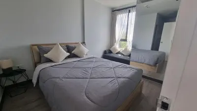 a bedroom with a bed and a chair and a window at IKON STAY Zcape 2 Condominium S in Bang Tao Beach