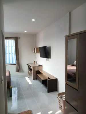 a room with a bed and a desk and a television at Sila Apartment in Ban Thalat Choeng Thale