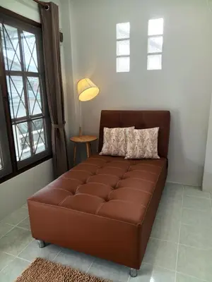 a brown leather couch in a living room with a lamp at Sila Apartment in Ban Thalat Choeng Thale