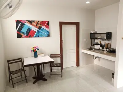 a room with a table and chairs and a kitchen at Sila Apartment in Ban Thalat Choeng Thale