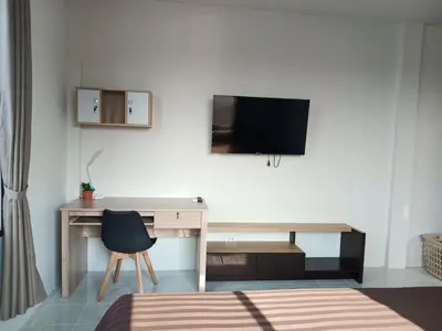 a room with a desk and a tv on a wall at Sila Apartment in Ban Thalat Choeng Thale