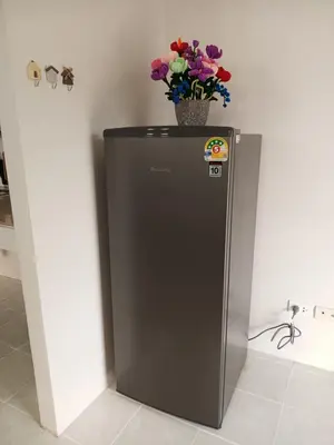 a black refrigerator with a basket of flowers on top at Sila Apartment in Ban Thalat Choeng Thale