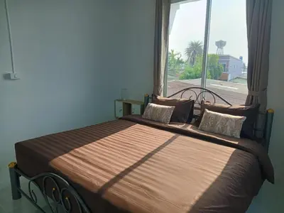 a bed in a room with a large window at Sila Apartment in Ban Thalat Choeng Thale