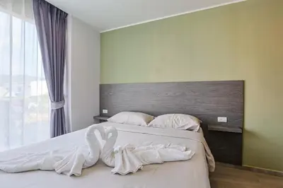a bedroom with a bed with white sheets and a large window at Big Buddha View - 1 bedroom T3 - 228 in Chalong
