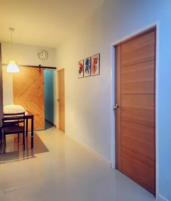 a hallway with a wooden door and a dining table at Damiya Peaceful House in Ban Bo Dan